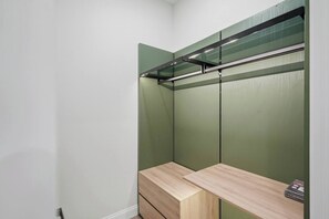 Ein begehbarer Kleiderschrank mit beschlagenem Kleiderstange und einer hölzernen Sitzbank.