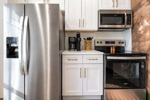 Eine Küche mit einem Edelstahl-Kühlschrank, einer Mikrowelle, einer Kaffeemaschine und einem Backofen.