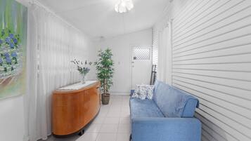 Una sala moderna con un sofá azul, un aparador de madera y una planta en maceta.
