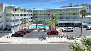 Een meerhoog hotel met een zwembad, parkeerplaats en een bord waarop 'PELICAN POINT' staat.