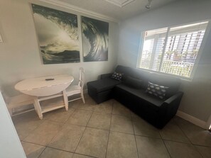 A small, modern room with a white round table, a black sofa, and two large abstract paintings on the wall. - Pelican Pointe 425:Walk to Beach~Pool~Free Parking (Clearwater Beach)