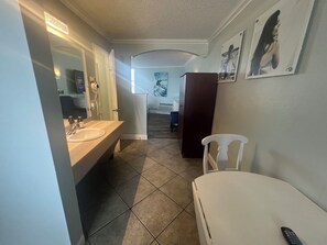 Un baño de hotel con lavamanos, espejo y una silla.