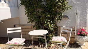A patio with two white chairs and a small table, surrounded by pebbles and a potted plant. - Rosmarie Vacation Rental—in the Heart of Rheinhessen (Alzey)