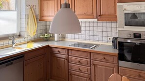 A kitchen with wooden cabinets, a white ceiling, a hanging pendant light, a microwave, and a dishwasher. - Rosmarie Vacation Rental—in the Heart of Rheinhessen (Alzey)