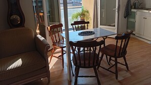 En matplats med ett bord och stolar, en soffa, en klocka och utsikt genom en glasdörr.