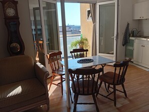 Ein Essbereich mit Tisch, Stühlen, einer Couch, einer Uhr und Blick durch eine Glastür.