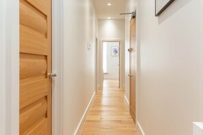 A hallway with wooden doors, white walls, and a wooden floor. - Modern Fitzrovia 3BR by Soho - London Centre (London)