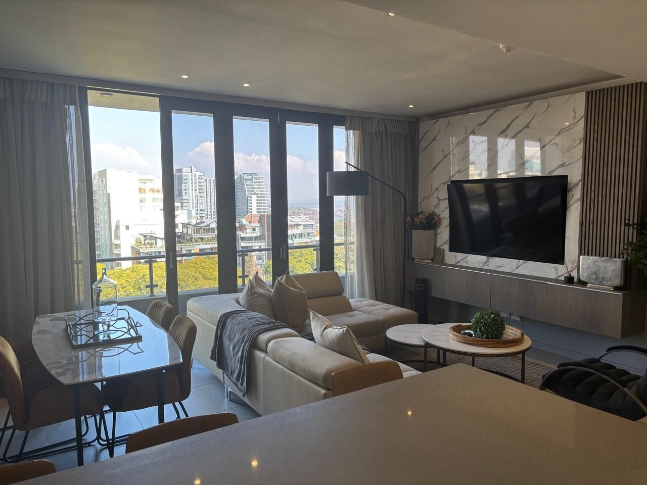 A modern living room with a sofa, a dining table, and a TV.