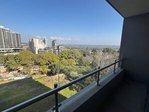 Een balkon met uitzicht op een stadsgezicht, inclusief gebouwen en bomen.