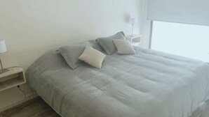 Ein Schlafzimmer mit einem Bett, Kissen, einem Nachttisch und einer Lampe.