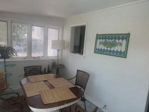 Ein Essbereich mit Tisch, Stühlen, einer Lampe und einem Fenster mit Jalousien.