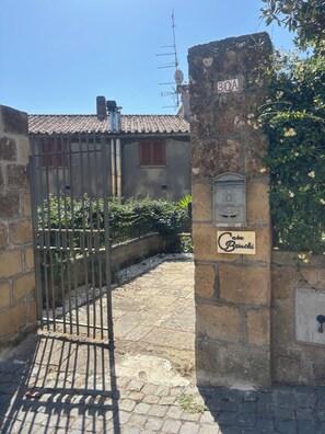 Une entrée fermée par un portail, un mur en pierre, une enseigne indiquant « Casa Brinchi » et un portail en métal.