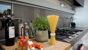 Eine Küchenarbeitsplatte mit einer Flasche, einer Pflanze, Spaghetti und Gemüse.