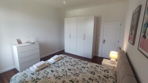 Ein Schlafzimmer mit Bett, Kommode, Kleiderschrank, Tür und Nachttischlampe.