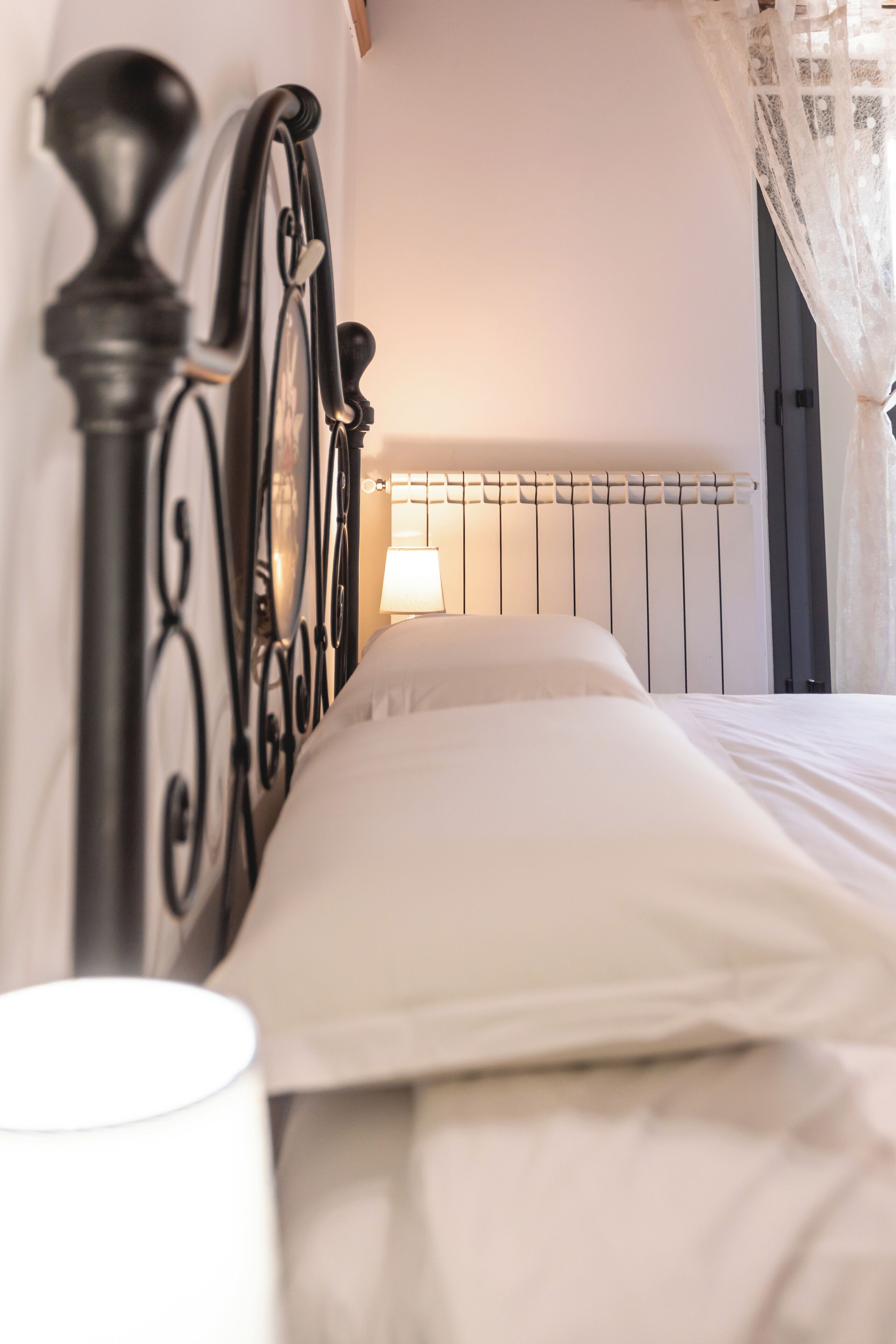 A bed with a metal headboard, a bedside lamp, and a radiator.