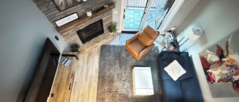 En moderne stue med en stenspir, et stort fladskærms-tv, en blå sofa og et tæppe med mønster.