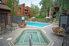 Ein Swimmingpool mit einer Tiefenmarkierung von etwa 90 Zentimetern, umgeben von Liegestühlen und Topfpflanzen.