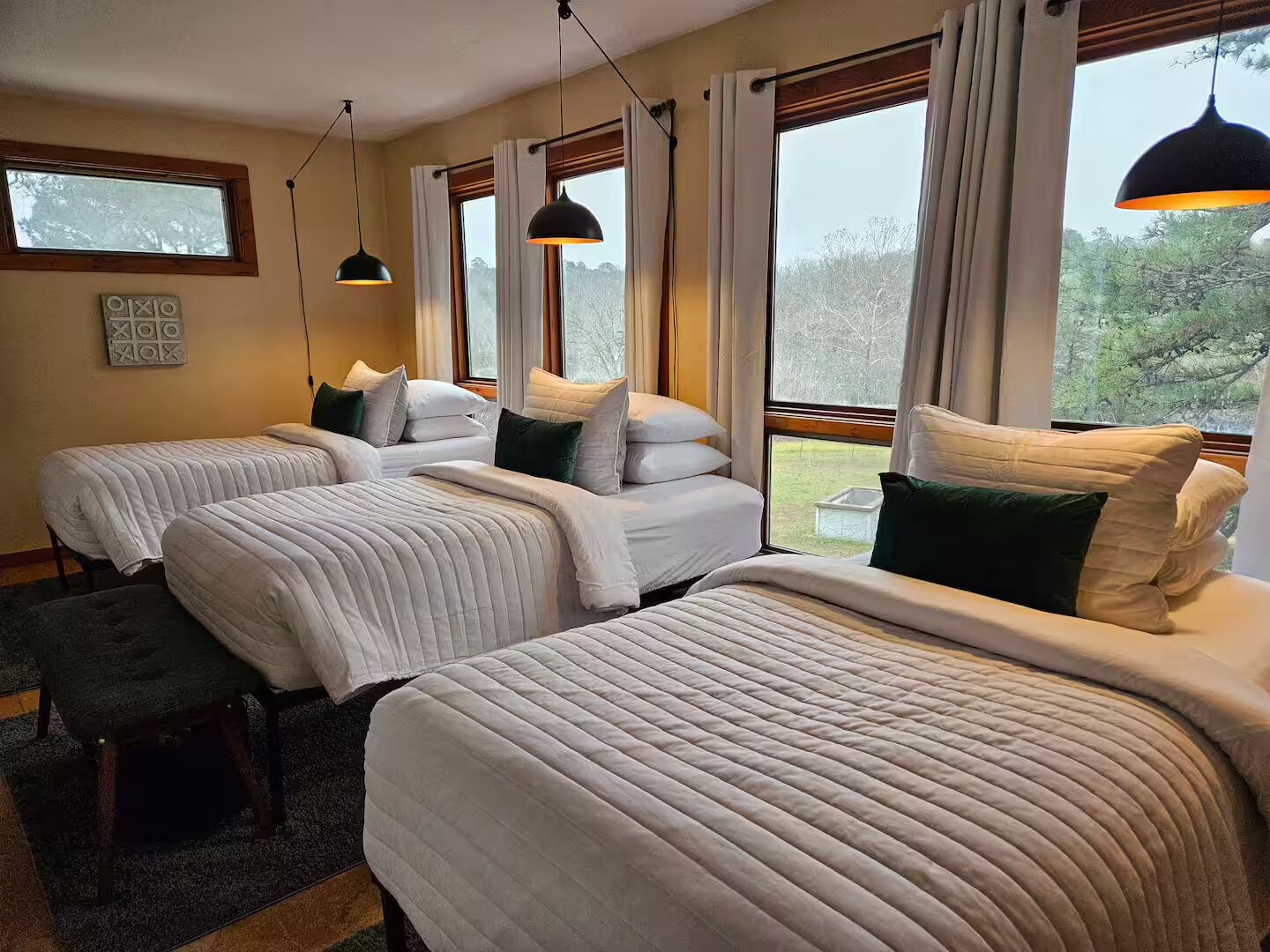 Ein Hotelzimmer mit zwei Betten, einer Sitzbank und einem Fenster mit Vorhängen.