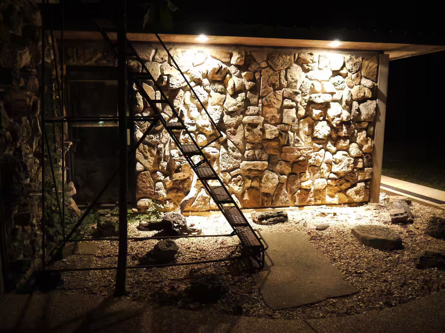 A stone wall with a metal staircase leading up to a door.