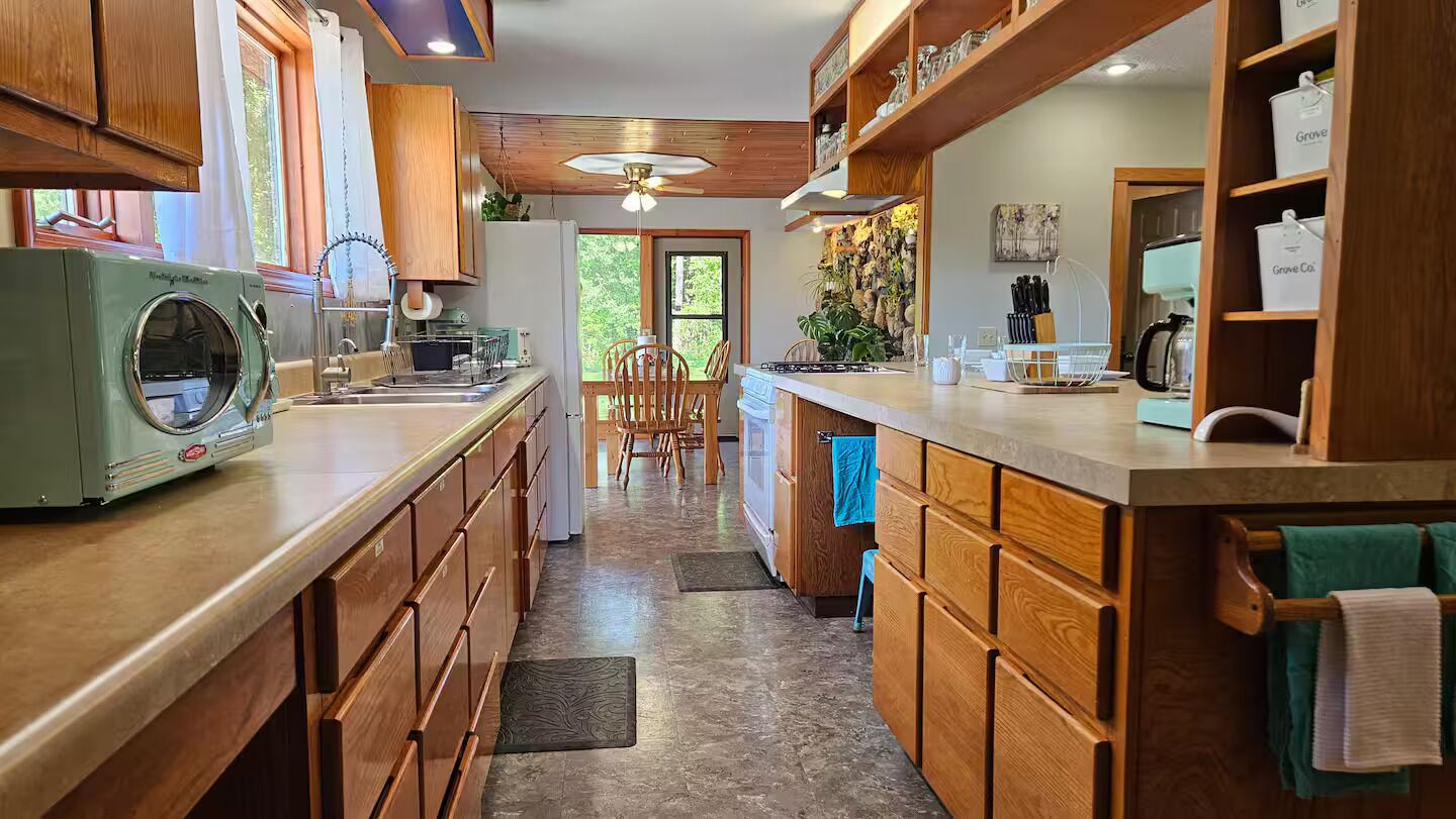 A kitchen with wooden cabinets, a built-in oven, and a dining area with chairs.