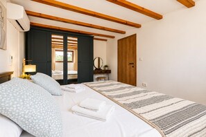A bedroom with a bed, a bedside table, a lamp, a wardrobe, and a door. - Villa Ika - Two Bedroom Villa, Sleeps 4 (Raštević)