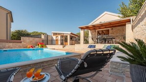 Ein Poolbereich mit Liegestuhl, Tisch mit Getränken und einer kleinen Spielanlage.