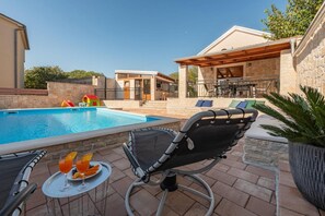 Ein Poolbereich mit Liegestuhl, Tisch mit Getränken und einer kleinen Spielanlage.