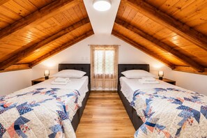 A room with two beds, wooden ceiling beams, a window with curtains, and a wooden floor. - Villa Ika - Two Bedroom Villa, Sleeps 4 (Raštević)