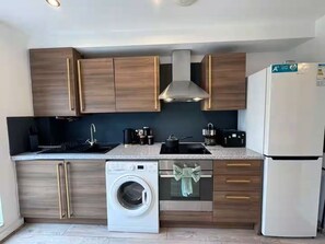 A compact kitchen with a built-in washer, a stove, and a refrigerator. - 3BR Contractor House By ELS Property Group Salford (Salford)