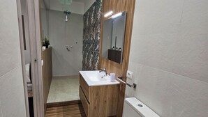 Et moderne badeværelse med en trækommode, toilet og bruseområde.