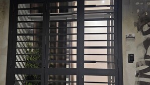 En metalport med vandrette ribber, en plantekasse til venstre og en mur med et nummer