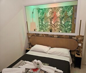 Ein Bett mit Kopfteil, ein an der Wand befestigter Spiegel und ein Handtuchhalter.