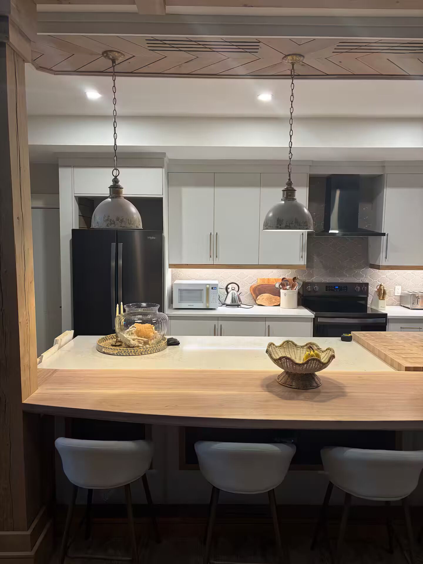 Une cuisine moderne dotée d’un îlot central, de meubles blancs et d’appareils électroménagers en acier inoxydable.