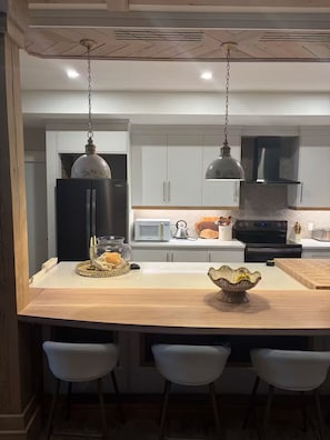 A modern kitchen with a central island, white cabinetry, and stainless steel appliances.