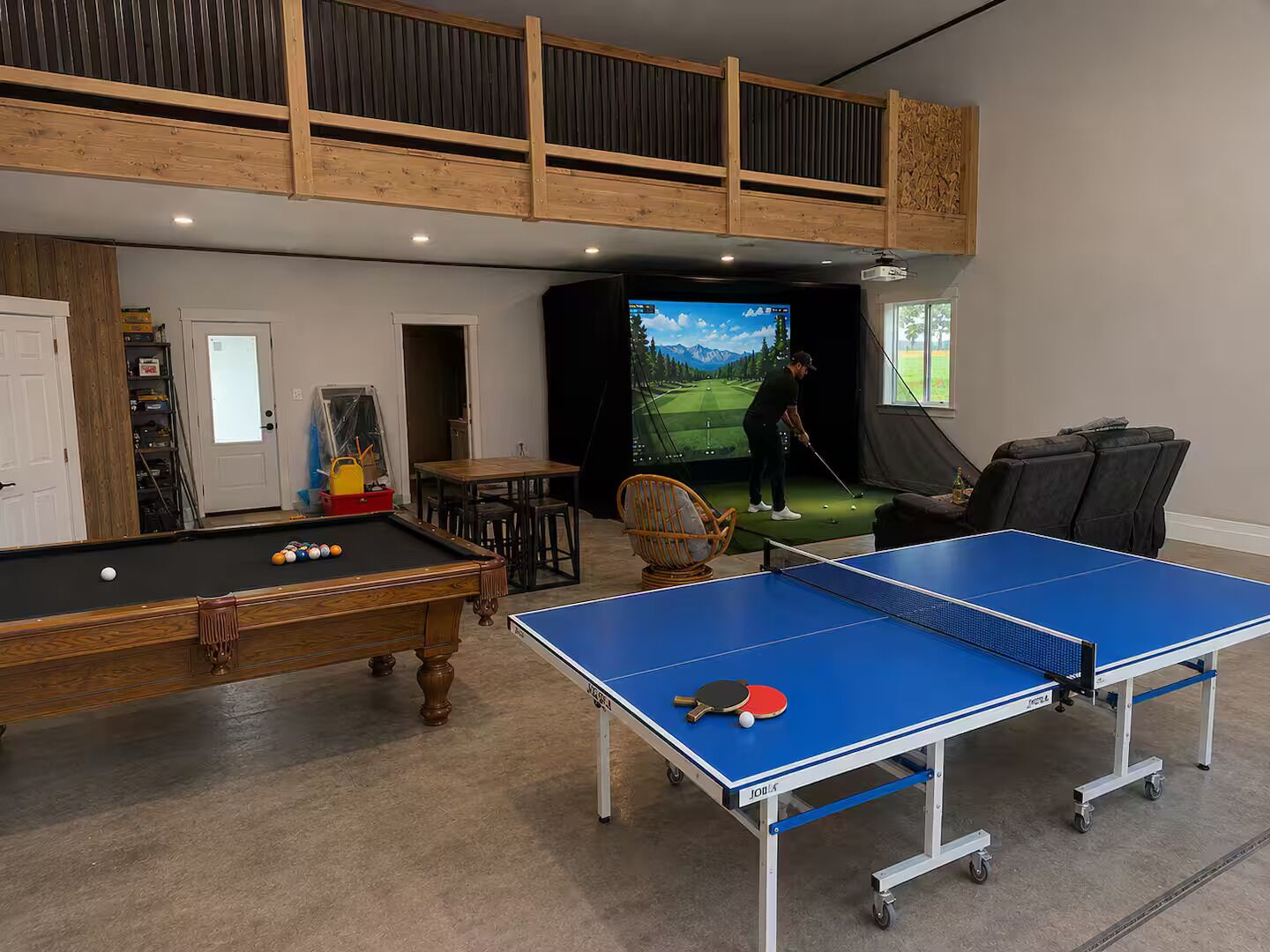 Une salle de loisirs équipée d’une table de billard, d’une table de ping-pong et d’un simulateur de golf.