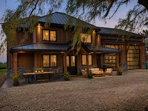 A two-story house with a covered patio, stone foundation, and large windows.