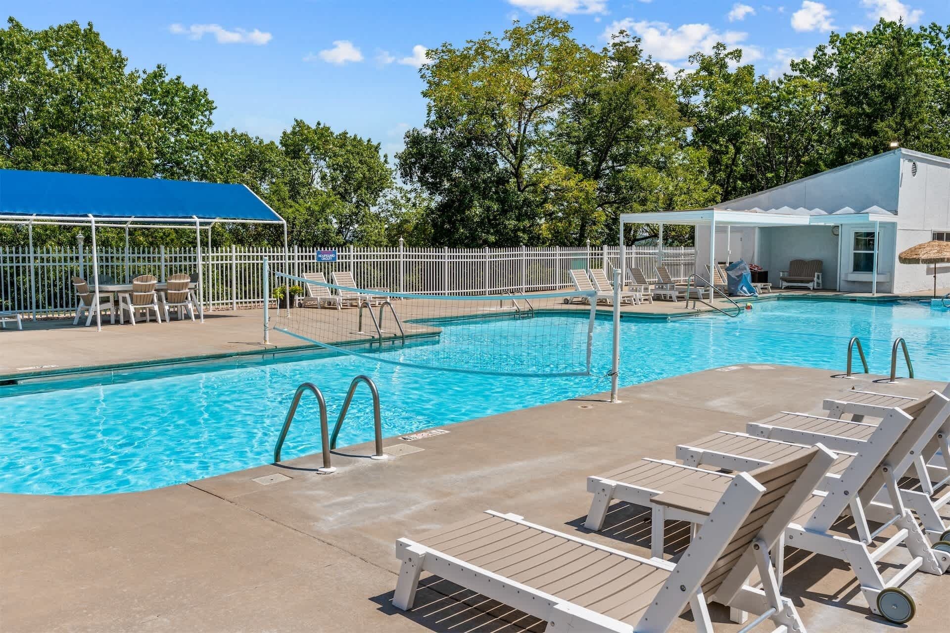 A swimming pool with lounge chairs and a covered seating area.