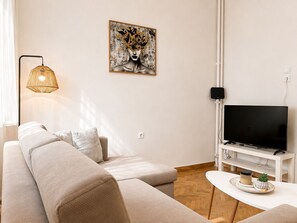 Un salon moderne avec un canapé, un téléviseur à écran plat, une œuvre d’art accrochée au mur et une lampe sur pied.