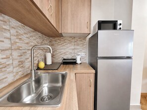 A modern kitchen with a stainless steel sink, wooden cabinets, a microwave, and a refrigerator. - Athens Base Αpt - Near Metro & Museum by ΜΡS (Athina)