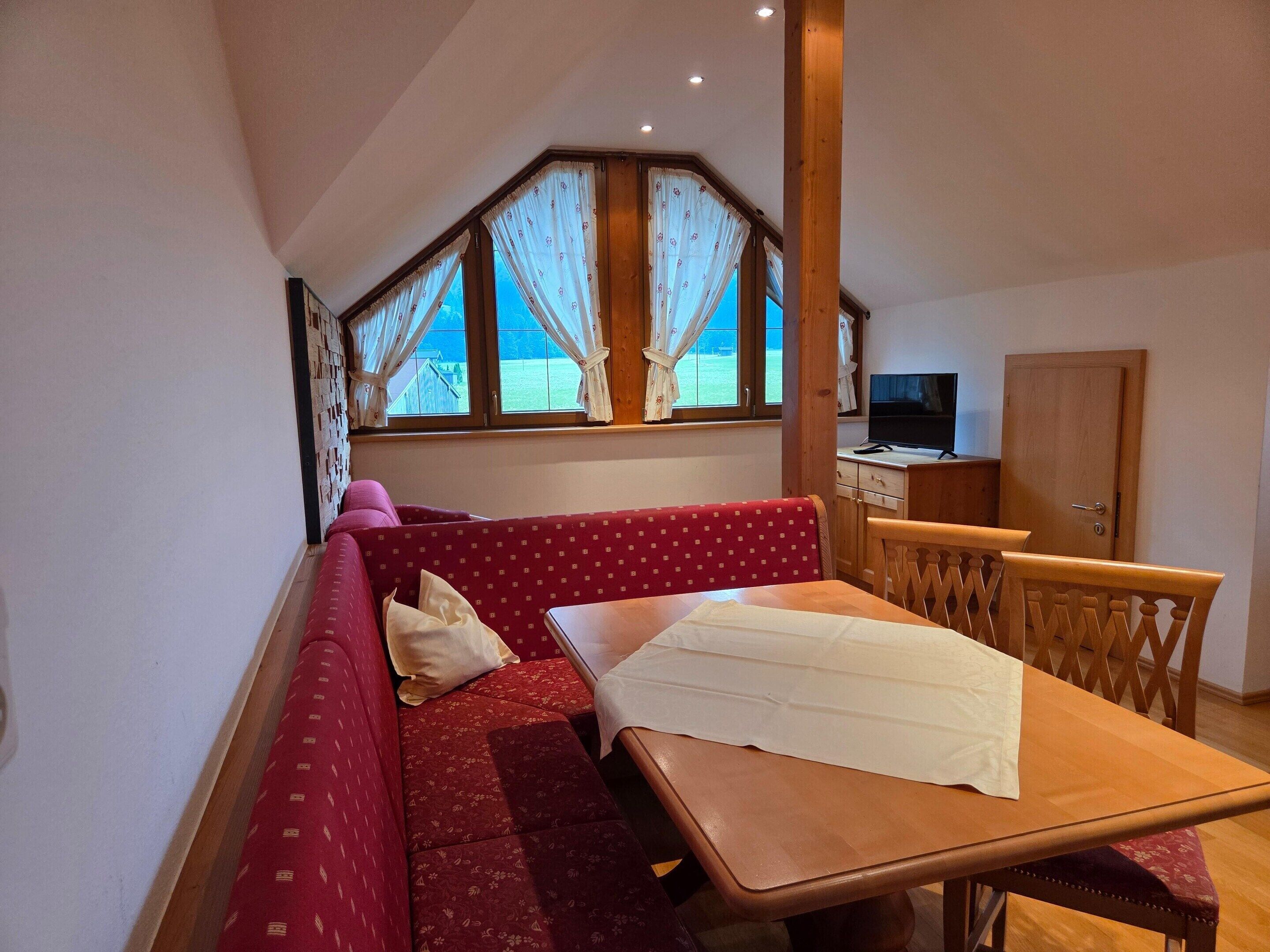 A cozy room with a red sofa, a wooden table, and a TV.