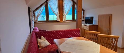 Um quarto aconchegante com um sofá vermelho, uma mesa de madeira e uma televisão.