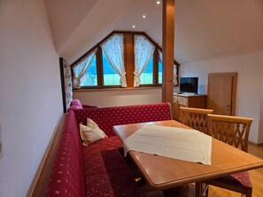 A cozy room with a red sofa, a wooden table, and a TV. - Holiday Apartment in an Alpine Setting (Achenkirch)