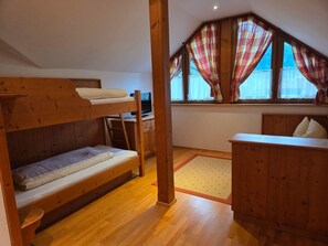 A room with a bunk bed, a desk with a computer, a small dresser, and a window with curtains. - Holiday Apartment in an Alpine Setting (Achenkirch)