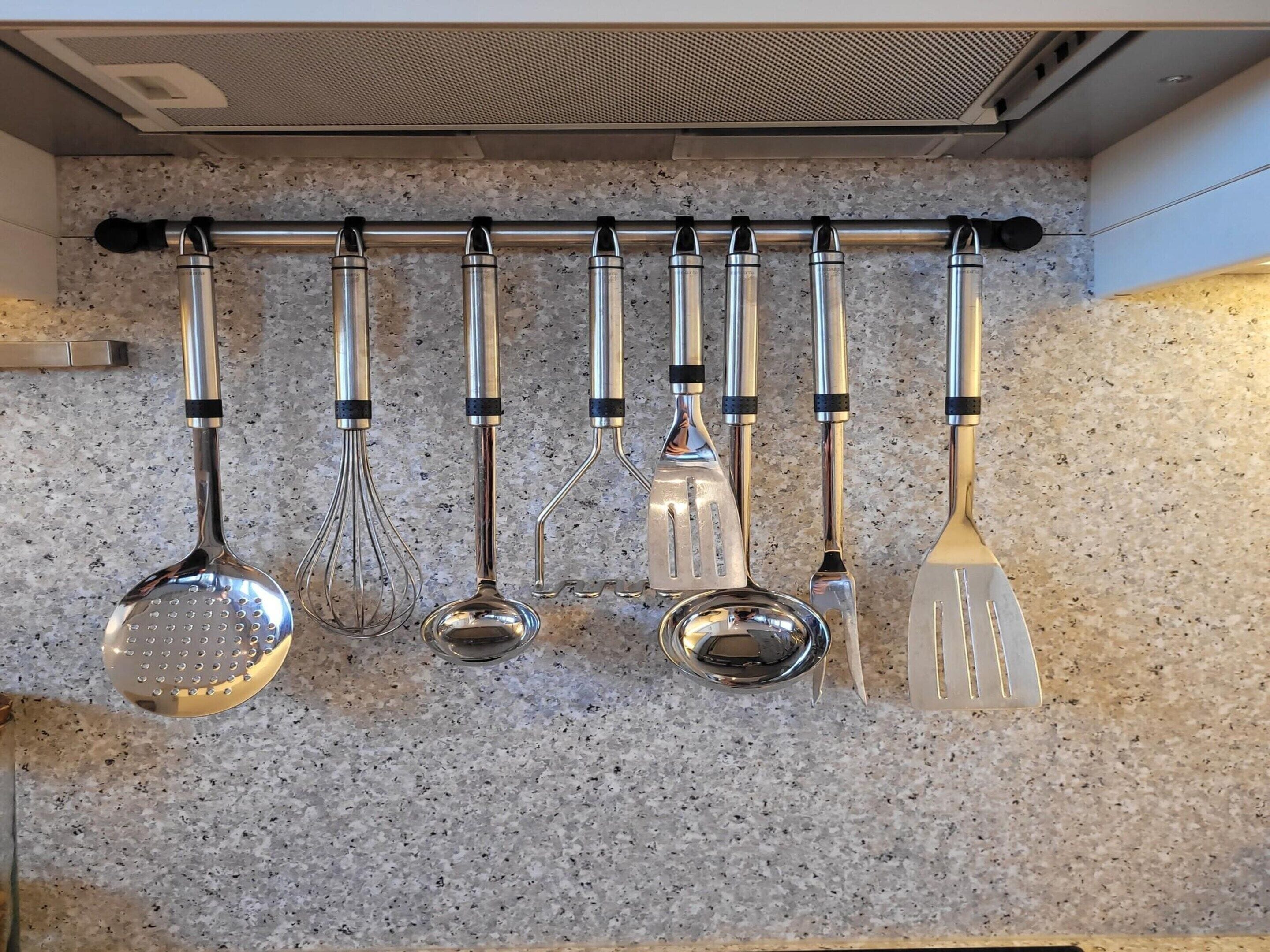 A kitchen with a stainless steel utensil rack holding various kitchen tools.