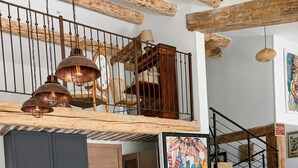 A modern kitchen with a central island, a wooden staircase, and a dining area with a rustic cabinet.