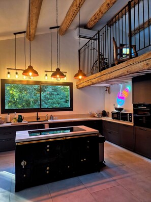 A modern kitchen with a central island, pendant lighting, and a large window with a view of greenery. - Mas La Fontaine de Pernes, right on the banks of the Sorgue River, with a pool, sleeps 12, 6 bedrooms, 5 bathrooms (Pernes-les-Fontaines)