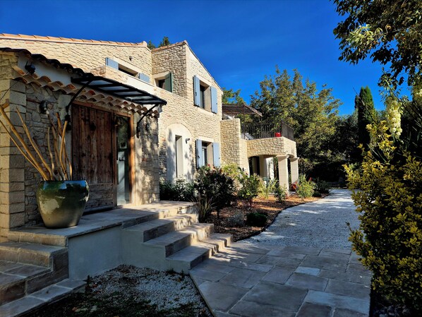 A stone building with a courtyard, steps leading to the entrance, and a potted plant.