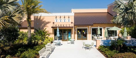 Un bâtiment avec une enseigne indiquant « MARCHÉ », des tables à l’extérieur et une enseigne indiquant « BAR ET GRILLE ».