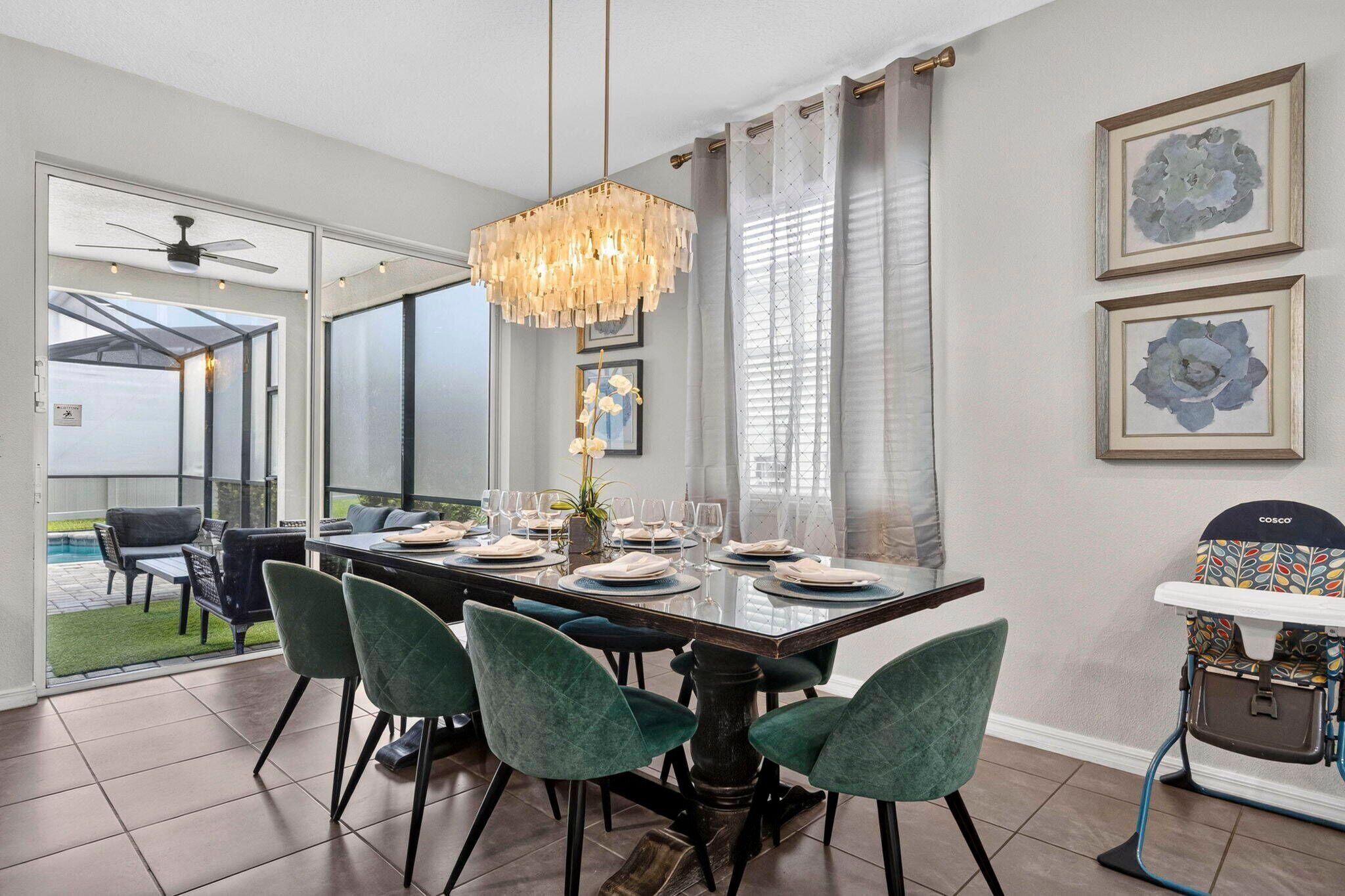 Un comedor con una mesa dispuesta para cuatro, una araña y vistas al exterior.