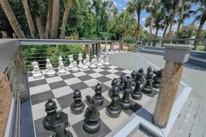 A chessboard set up outdoors with large chess pieces, surrounded by palm trees and a clear sky. - Orlando | Park Trip Base Stay | Pool + Golf (Lake Buena Vista)